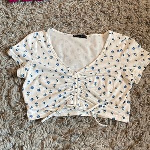 white cropped top with blue flowers, synched in the middle with a tie